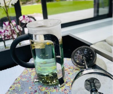 niebieska herbata emotea w teapress na stole w tle ogród z