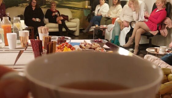 filiżanka z herbata emotea w tle kobiety siedzące w okręgu