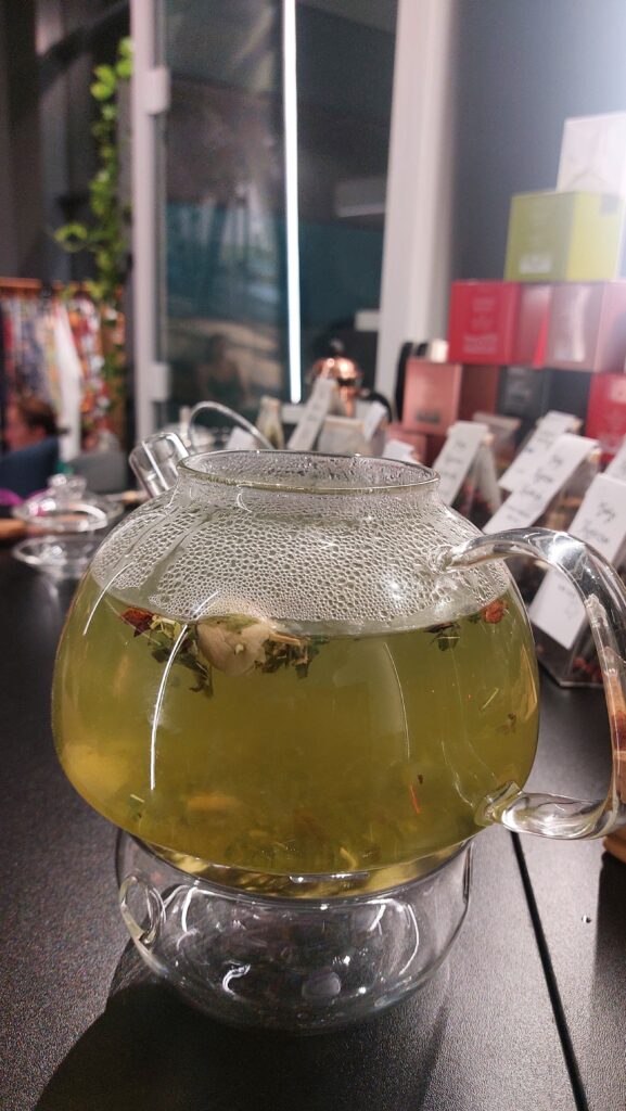 szklany dzbanek z herbata emotea Harmony w tle puszki herbat i gaiwan