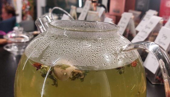 szklany dzbanek z herbata emotea Harmony w tle puszki herbat i gaiwan
